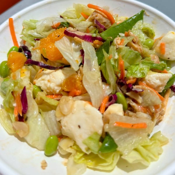 A vibrant Fuel Counter salad with lettuce, mandarin oranges, edamame, carrots, and chicken.