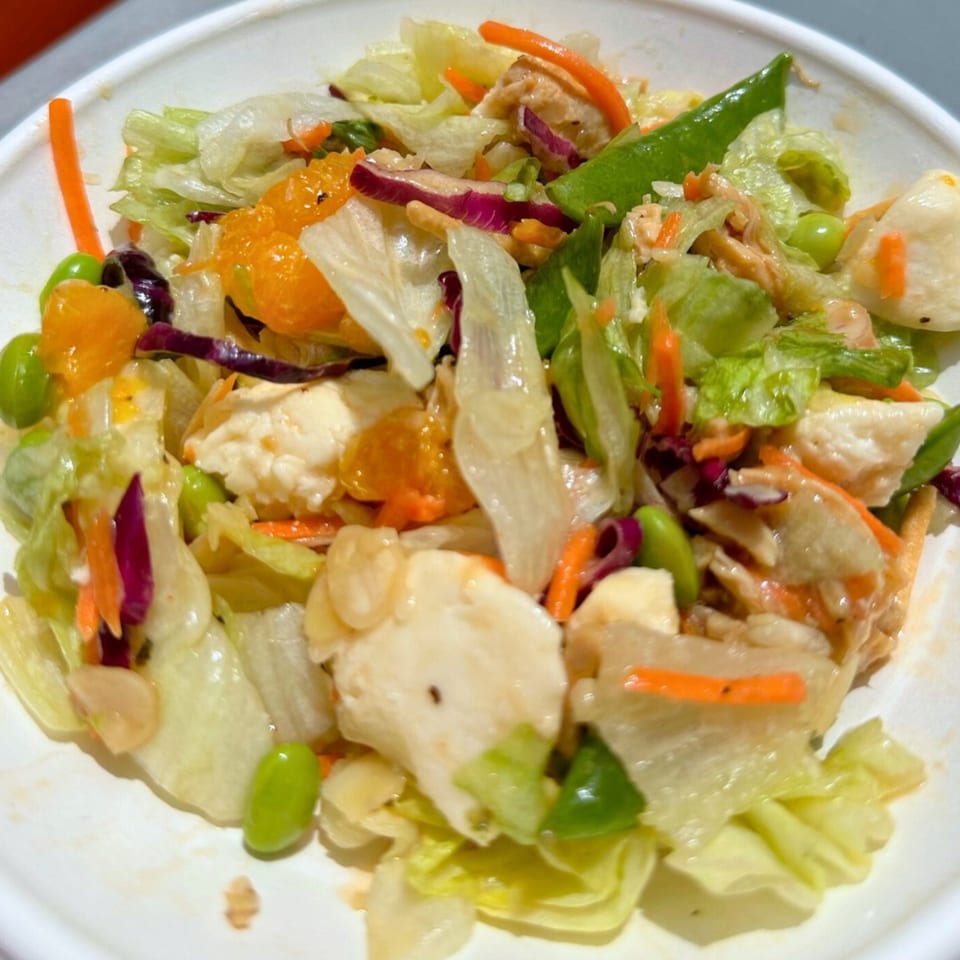 A vibrant Fuel Counter salad with lettuce, mandarin oranges, edamame, carrots, and chicken.